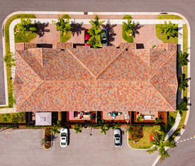 Overhead view of a tile-roofed residential building and its parking area