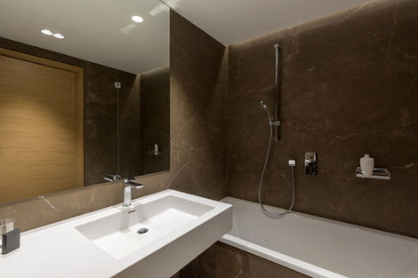 Remodeled bathroom with dark marble walls, a floating vanity and a walk-in shower