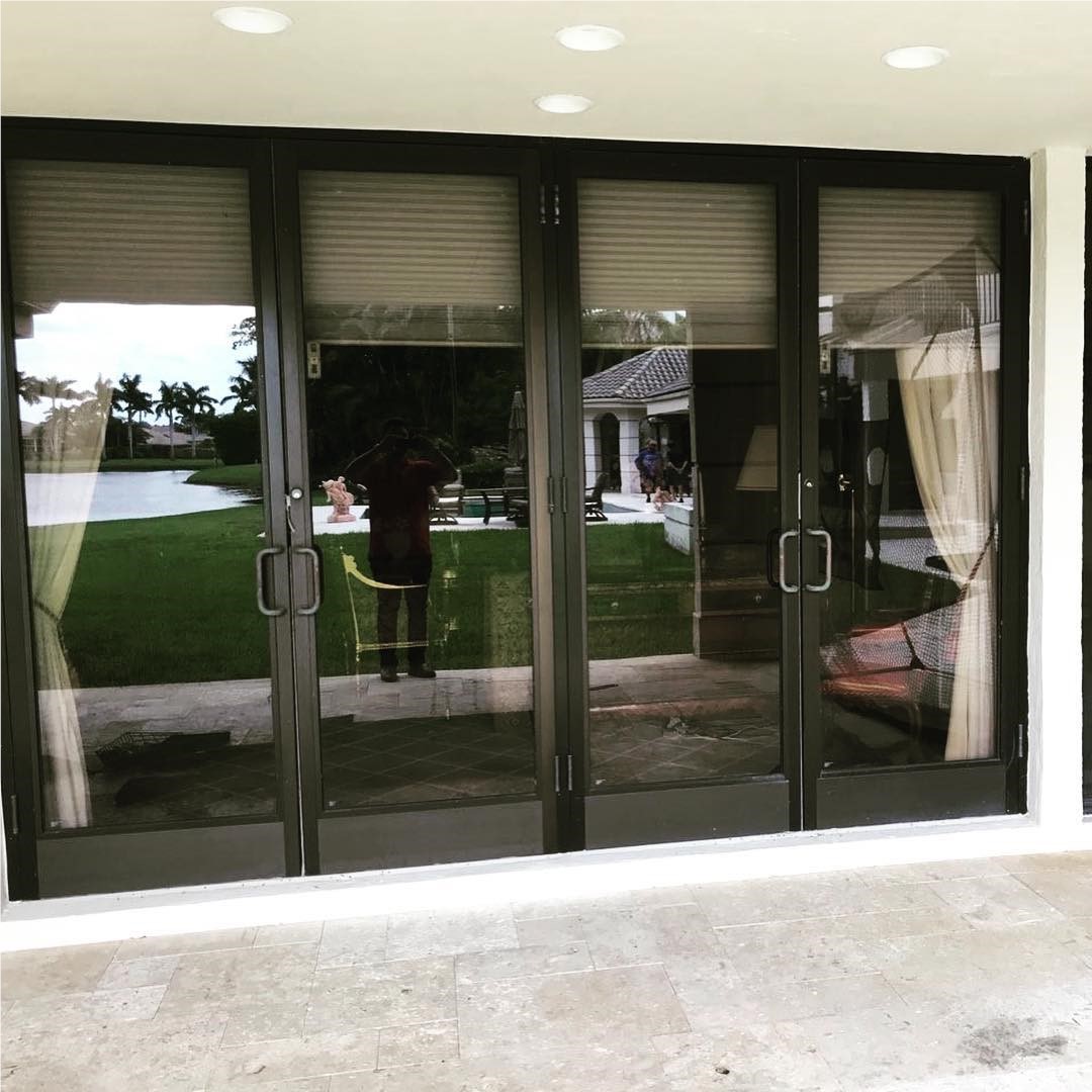 Bronze-framed impact French doors with sidelites facing a lawn and waterway