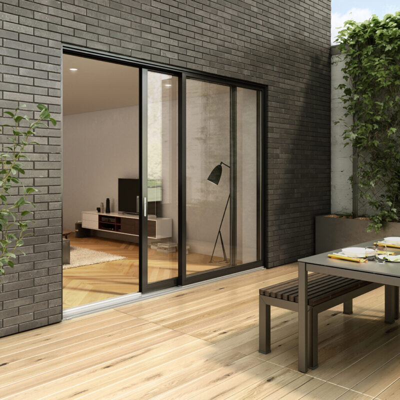 Black-framed sliding glass door opening from a living room onto a brick patio