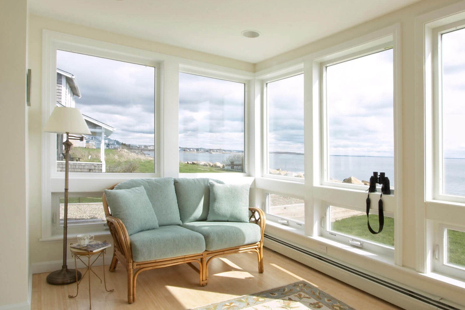 Sunroom featuring white-framed impact windows with a water view