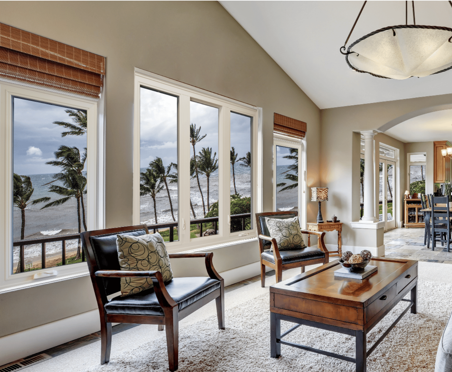 Living room with white impact windows overlooking palm trees and the ocean