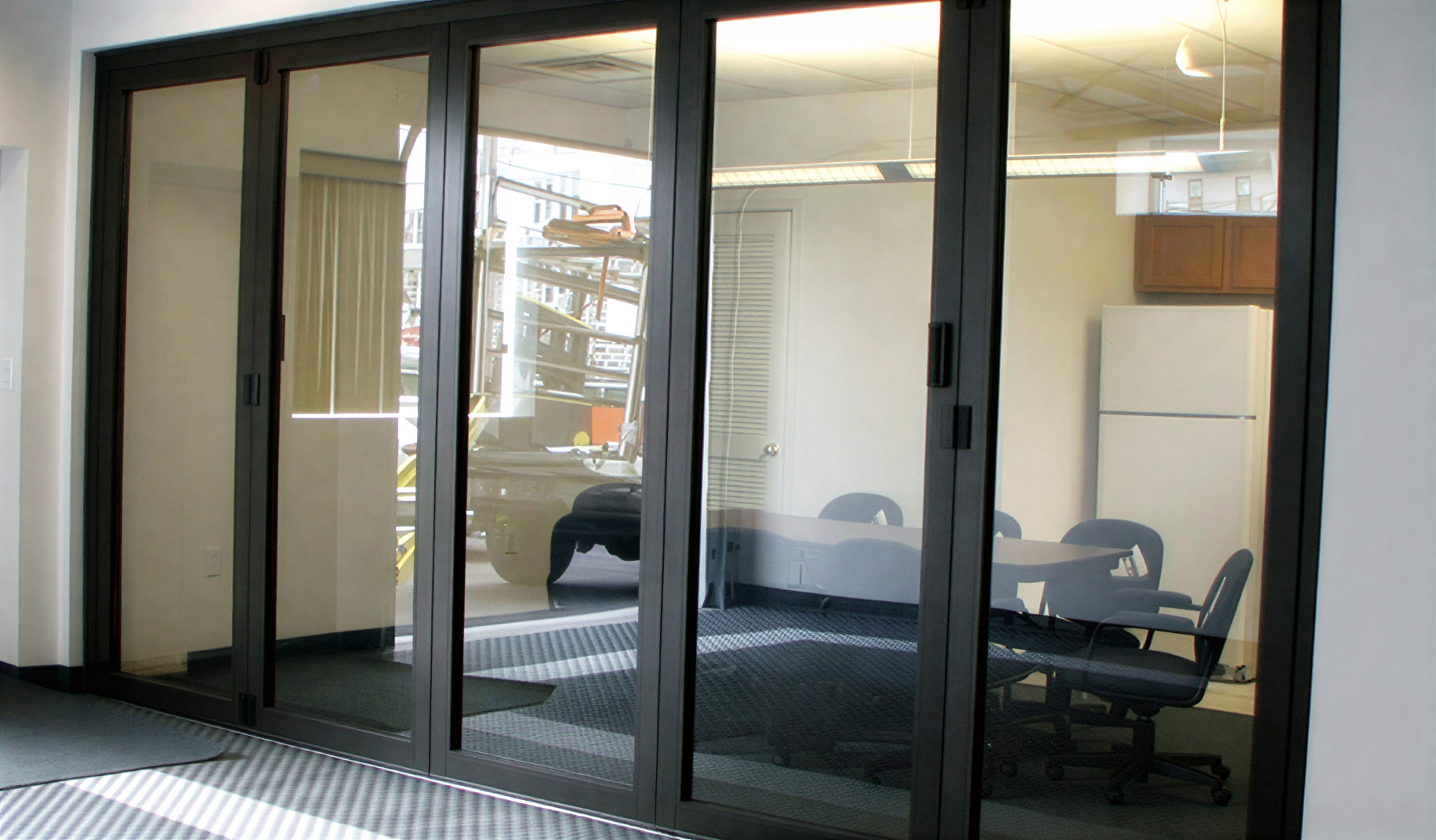 Black aluminum-framed impact sliding glass doors installed in a commercial office