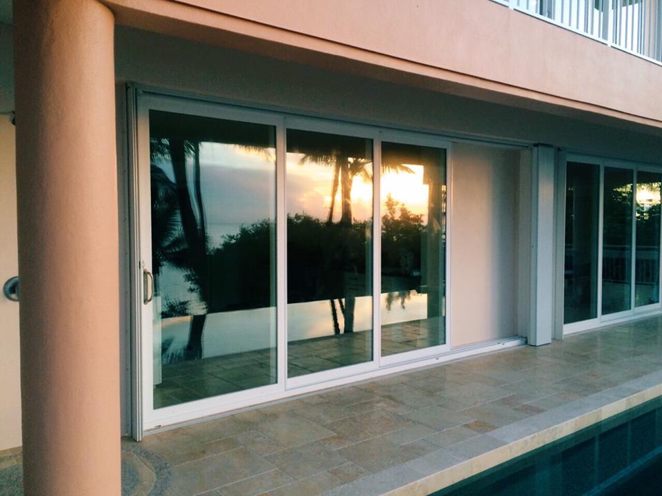 Sliding glass impact doors opening onto a pool deck at sunset