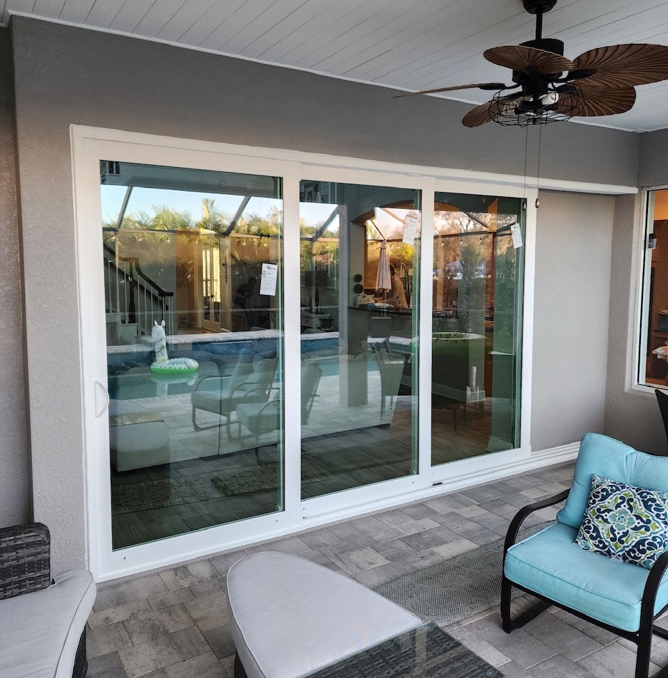 Hurricane-rated white sliding glass door on a covered patio overlooking a pool
