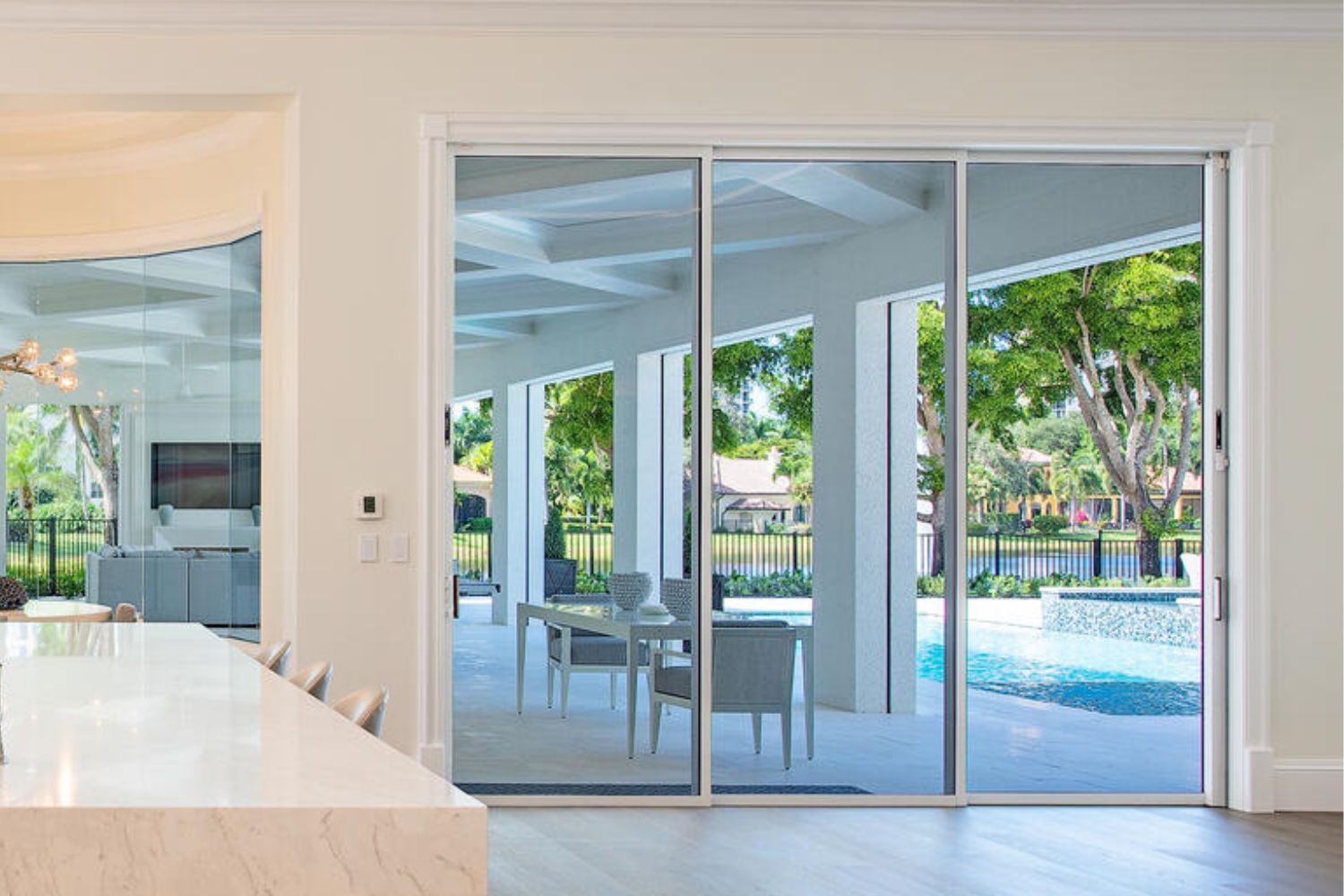 White-framed impact sliding glass doors in a kitchen overlooking the pool