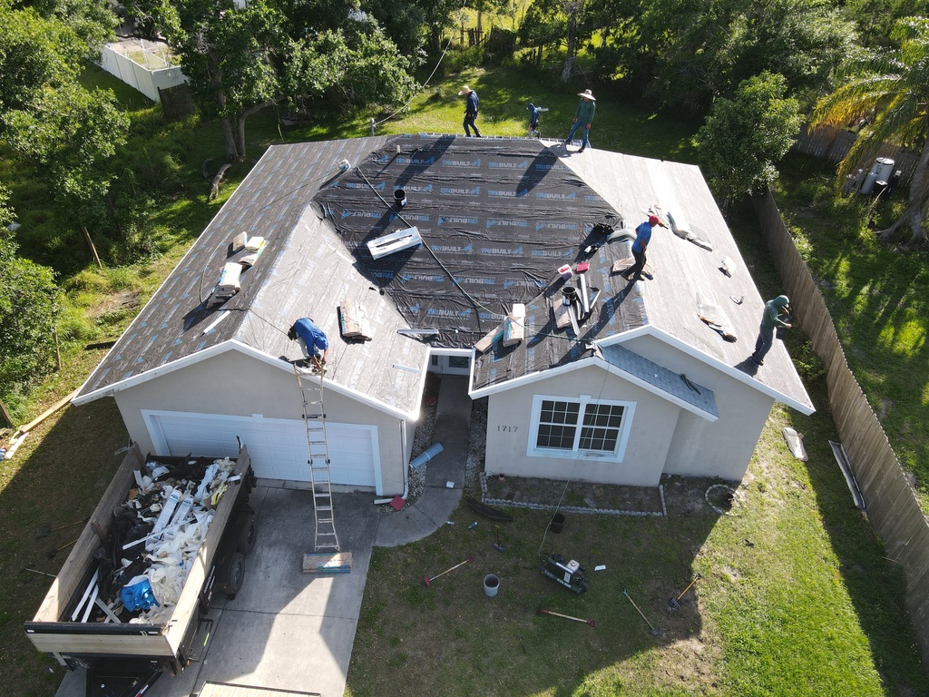 Aerial view of a residential roof replacement crew installing new shingles
