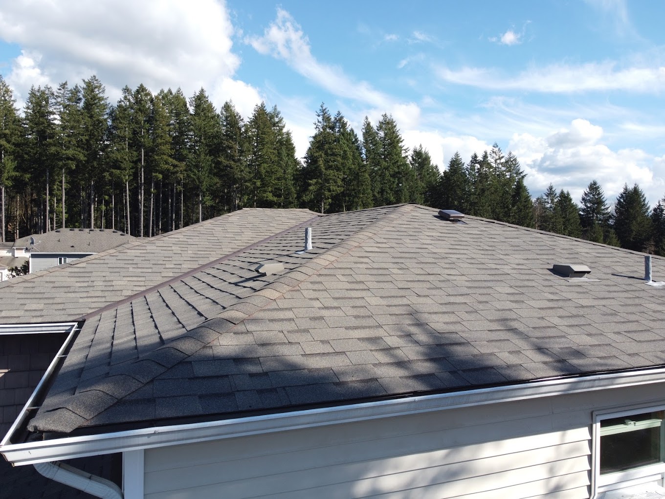 Grey architectural shingle roof on a residential home against a blue sky