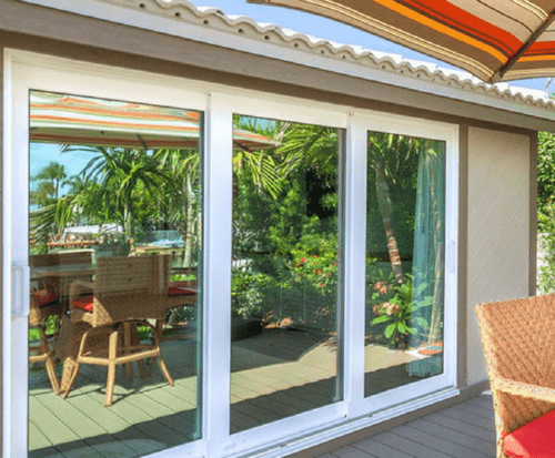 White-framed impact sliding glass doors opening to a tropical patio view
