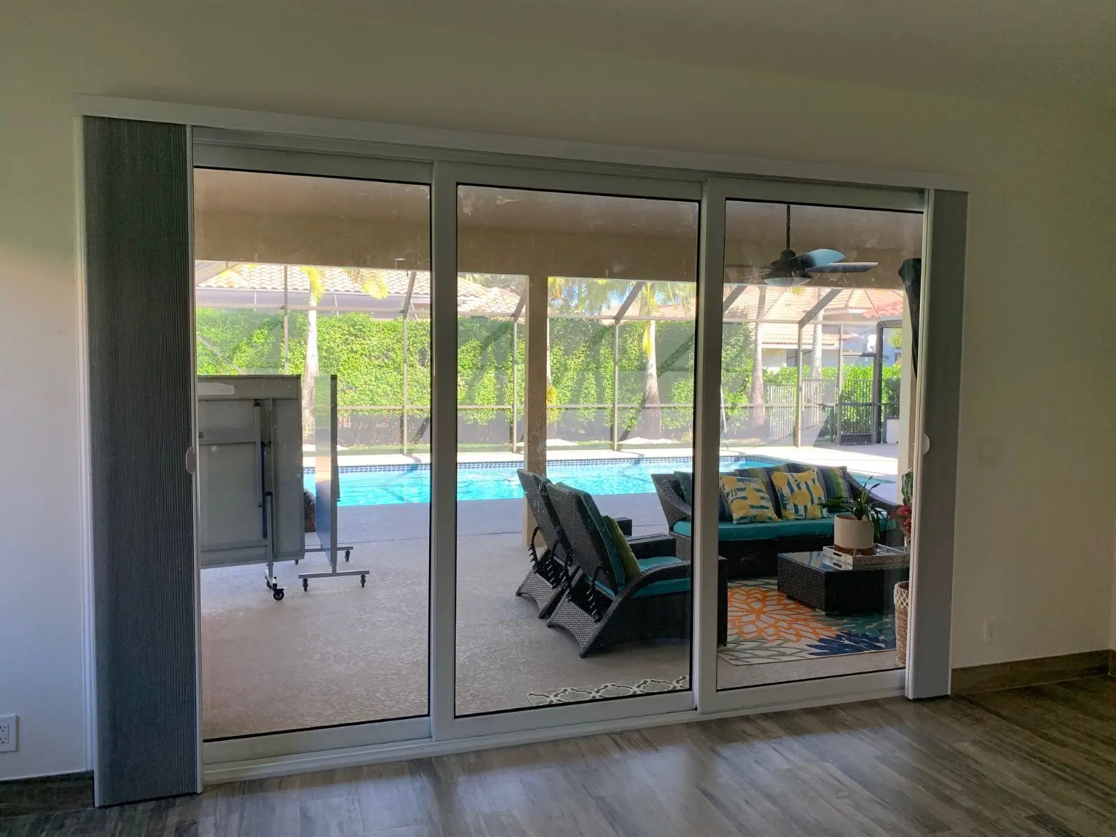 White aluminum sliding patio doors seen from inside a room facing a screened pool