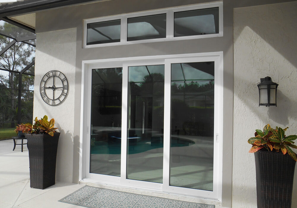 White-framed impact sliding glass door opening to a pool patio