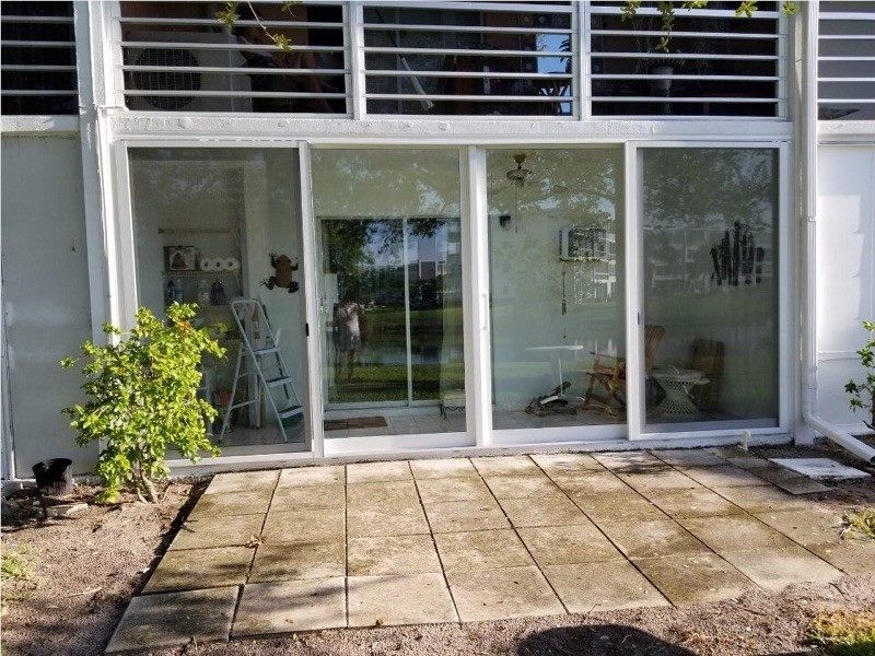 White sliding glass patio doors opening onto a paver patio