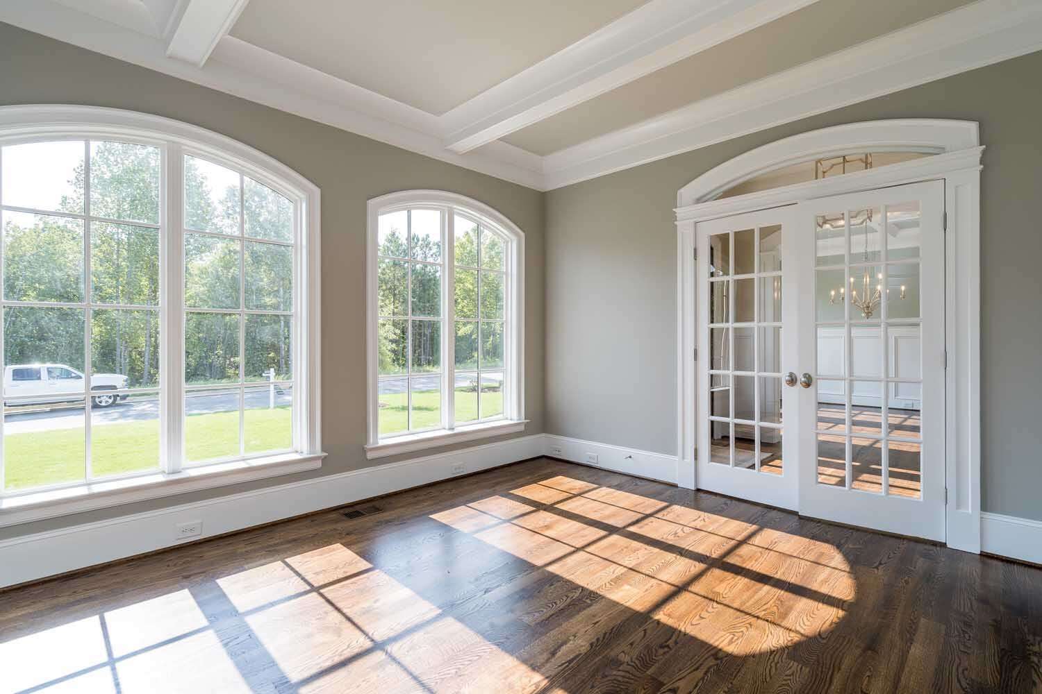 Living room with custom arch-top windows and white French doors