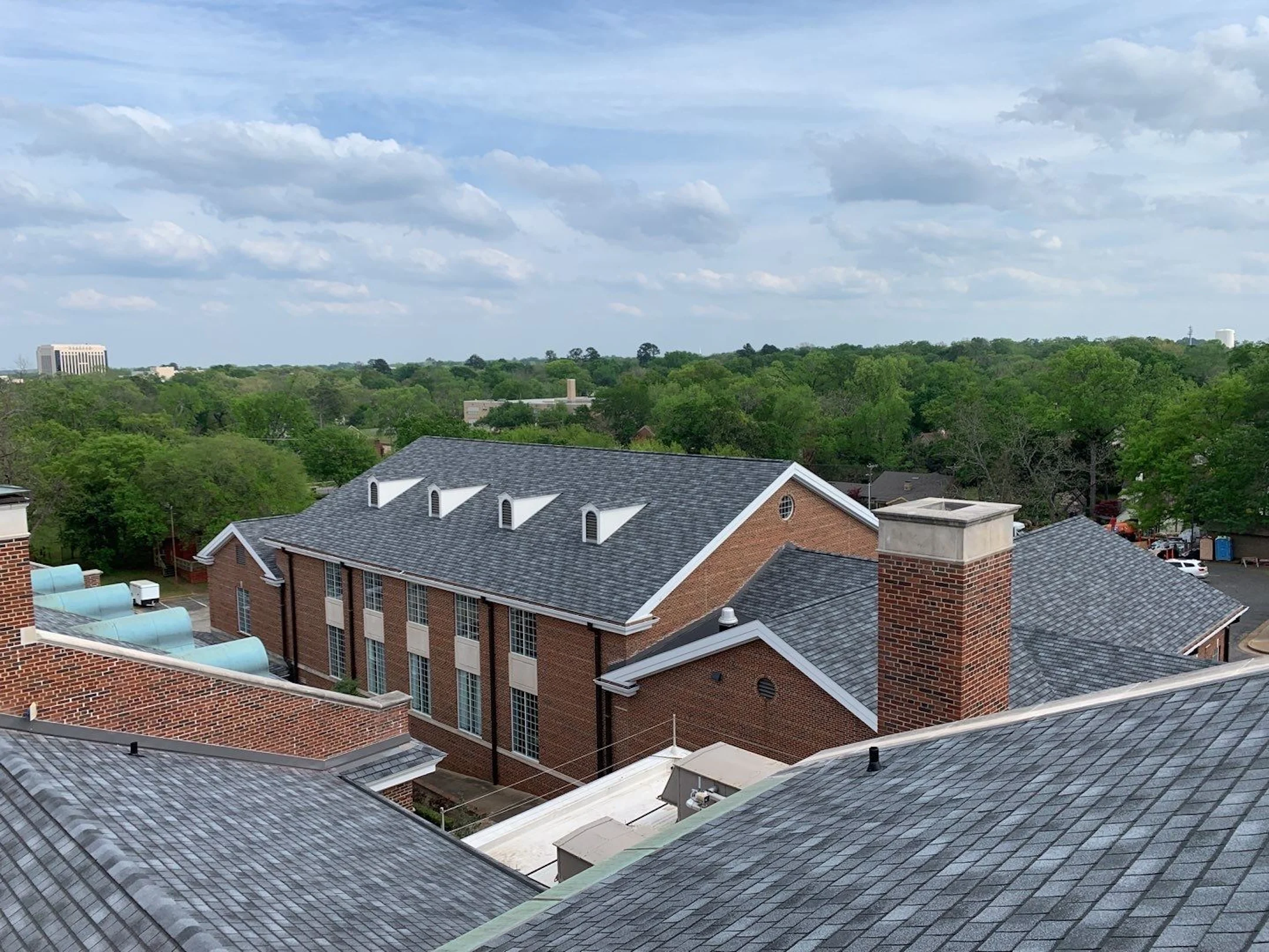Rooftop view of a brick building with a grey shingle roof