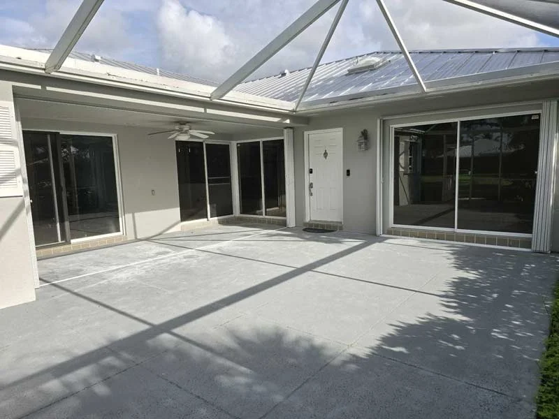 Screened pool enclosure with sliding glass doors along the rear of a home