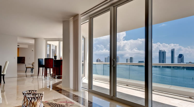 Condo interior with impact-resistant sliding glass doors opening to a waterfront balcony