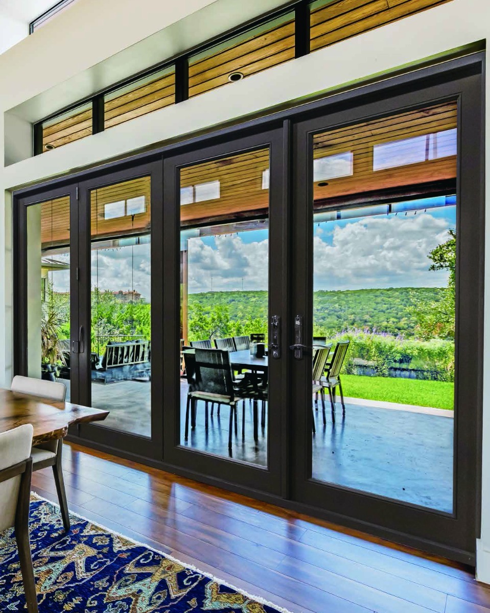 Dark-framed impact sliding glass doors opening from a dining room onto a patio
