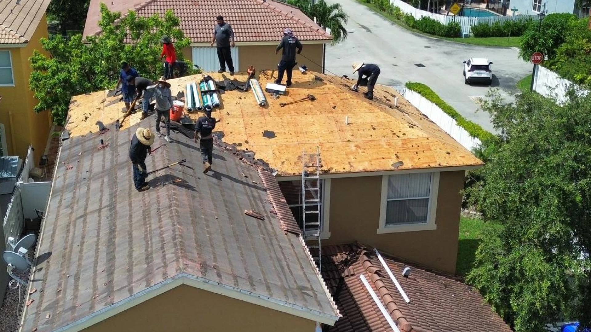 Aerial view of a roofing crew tearing off and replacing a tile roof