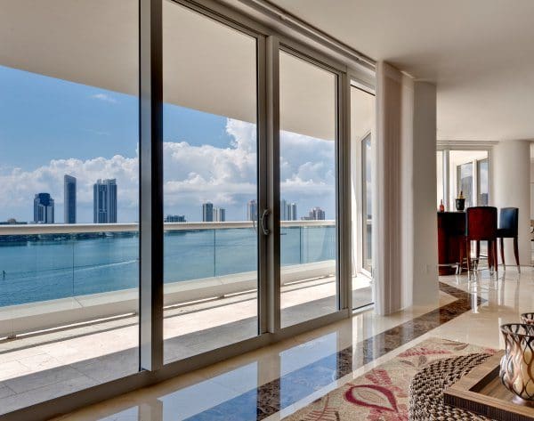 Condo interior with sliding glass doors opening onto a balcony above the bay